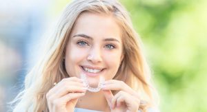 Puntillo and Crane Orthodontics, Orthodontic treatment and braces options, Girl smiling and holding an invisalign clear aligner