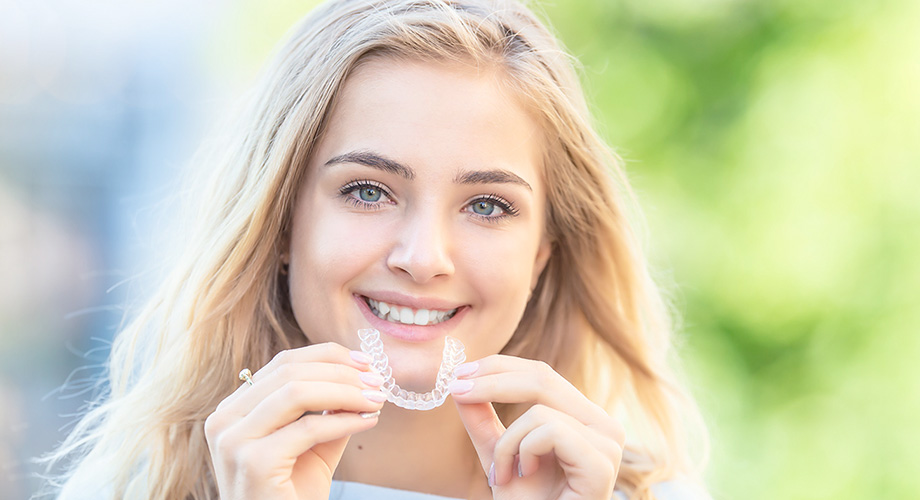 Puntillo and Crane Orthodontics, Orthodontic treatment and braces options, Girl smiling and holding an invisalign clear aligner