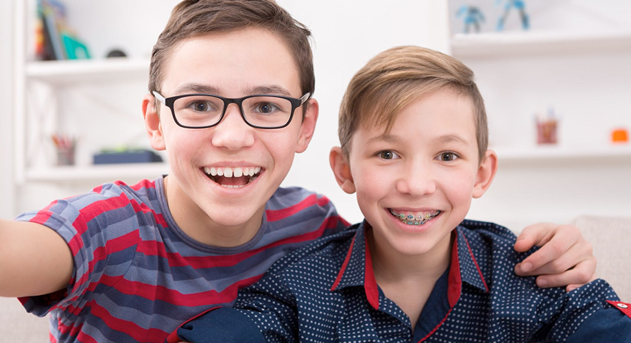 Puntillo and Crane Orthodontics, Early Orthodontic Treatment, Picture of two young brothers smiling and one has braces