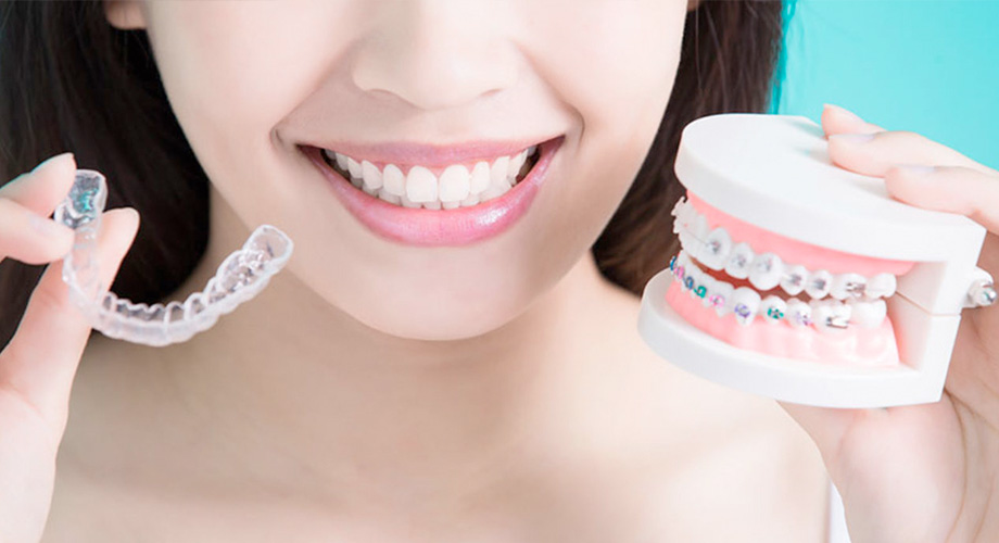 Puntillo and Crane Orthodontics, Types of Braces, Girl holding up choices between clear aligners, or braces