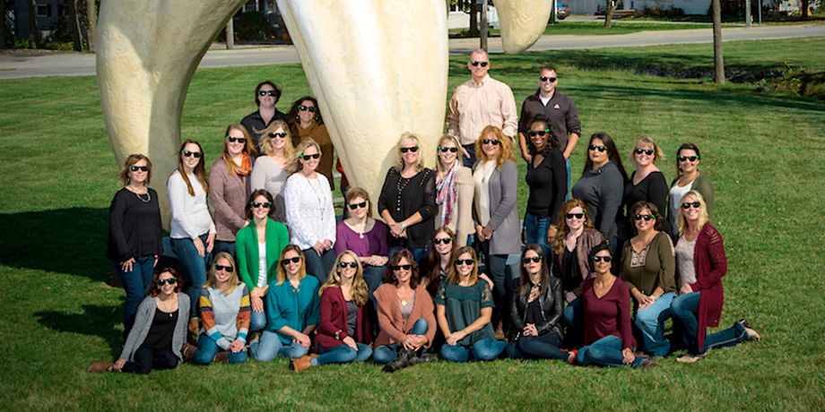Puntillo and Crane Orthodontics, What sets us apart, Image of the whole team at P and C standing near a giant tooth